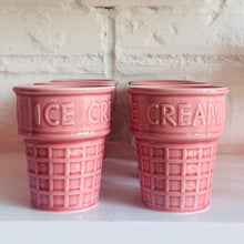 Load image into Gallery viewer, Two pink ceramic ice cream cone cups with embossed 'ICE CREAM' text, sitting on a white shelf against a white brick wall.
