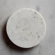 Load image into Gallery viewer, A round white marble coaster with subtle gray and brown veining, photographed from directly above on a matching marble surface.
