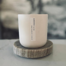 Load image into Gallery viewer, White candle on a marble coaster with a blurred natural background
