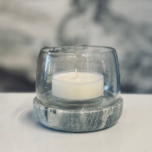 Clear glass candle holder with a white candle on a light surface