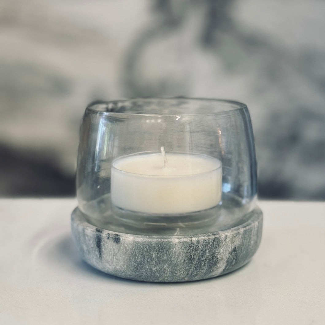 Clear glass candle holder with a white candle on a light surface
