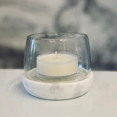 Clear glass candle holder with a white candle on a light surface