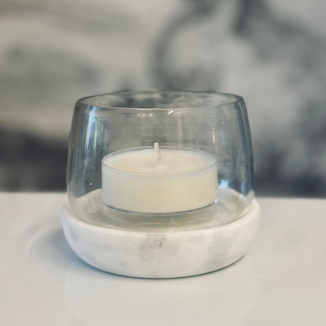 Clear glass candle holder with a white candle on a light surface