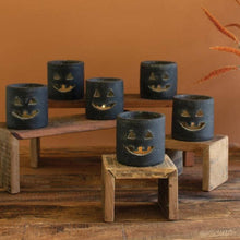 Load image into Gallery viewer, Set of blue candle holders with jack-o'-lantern faces on a wooden table against an orange wall.
